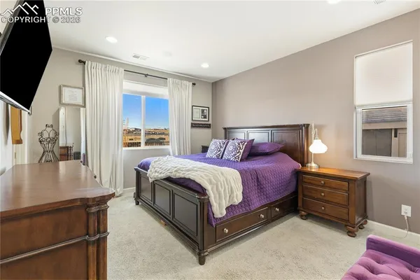 a spacious bedroom with a bed and a dresser with mirror