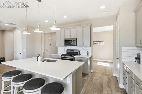 a kitchen with a sink a stove and chairs