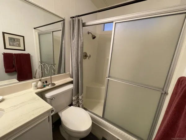 a bathroom with a sink a toilet a mirror and shower