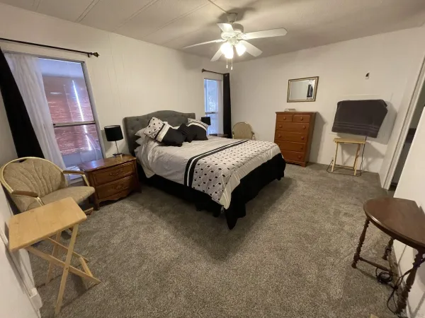 a spacious bedroom with a bed a chair and a chandelier