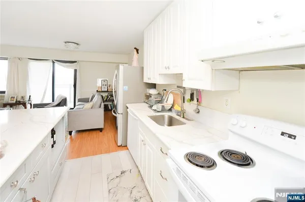 a kitchen with a sink a stove and white cabinets