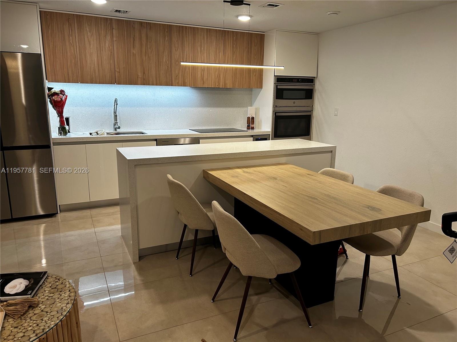 14569 Southwest 261st Terrace, Unit 14569 Homestead, FL 33032 - Photo 10 of 29 a kitchen with a kitchen island a stove a table and chairs