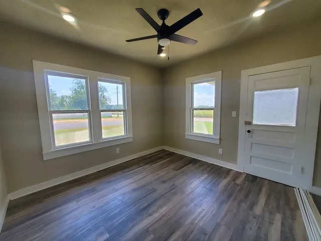 a view of an empty room with a window and wooden floor