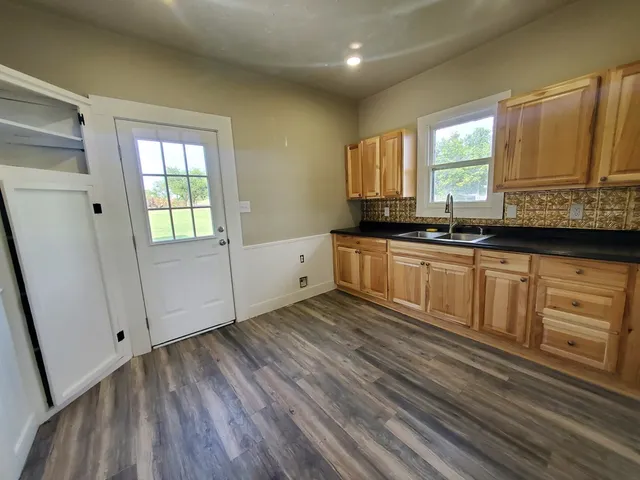 a kitchen with granite countertop a sink a stove cabinets and wooden floor