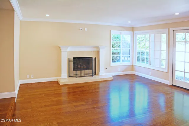 a view of empty room with wooden floor and fireplace