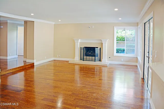 a view of empty room with wooden floor and fireplace