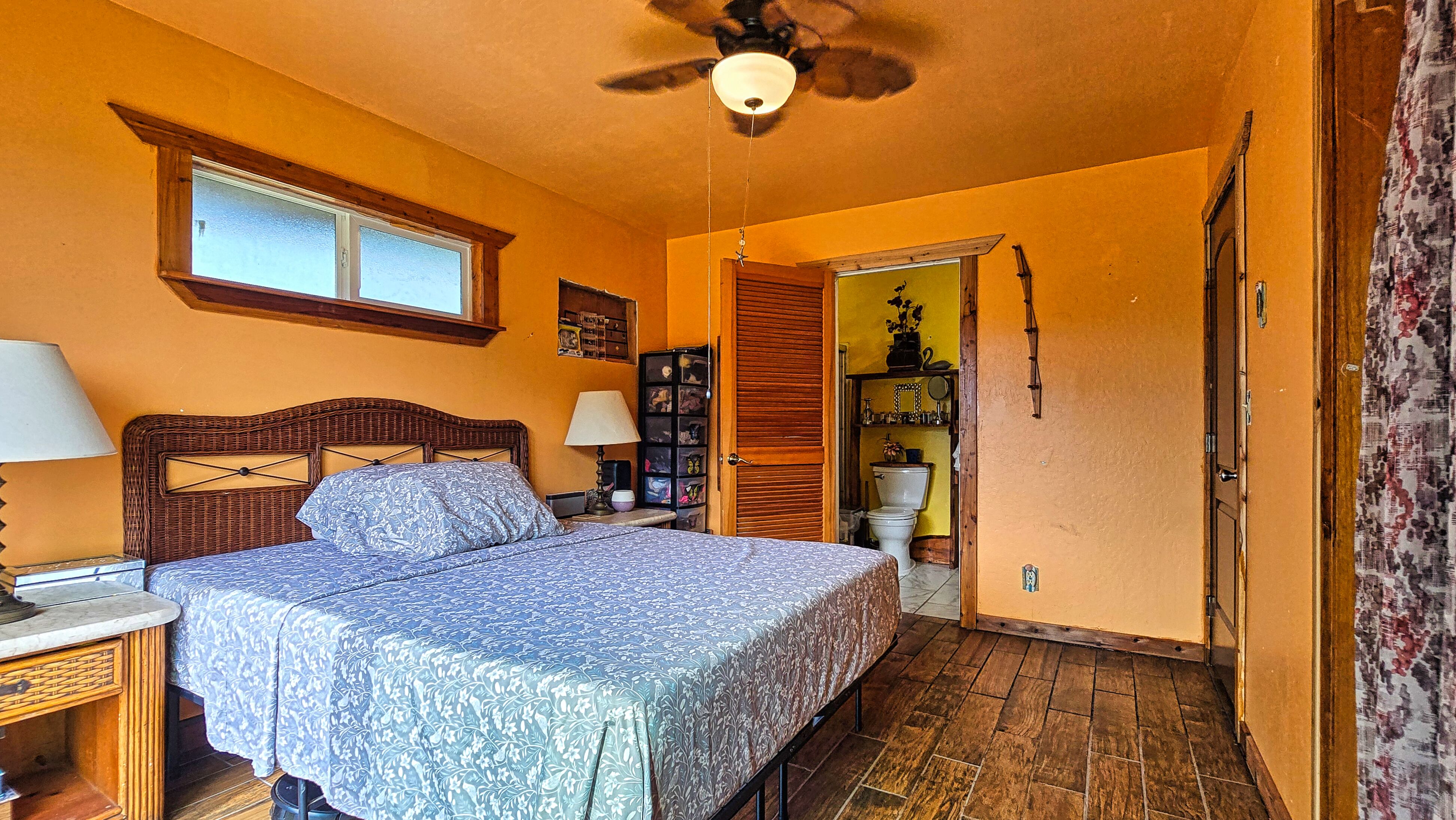 94-6491 Kamaoa Road Naalehu, HI 96772 - Photo 9 of 30 a bedroom with a bed and a chandelier