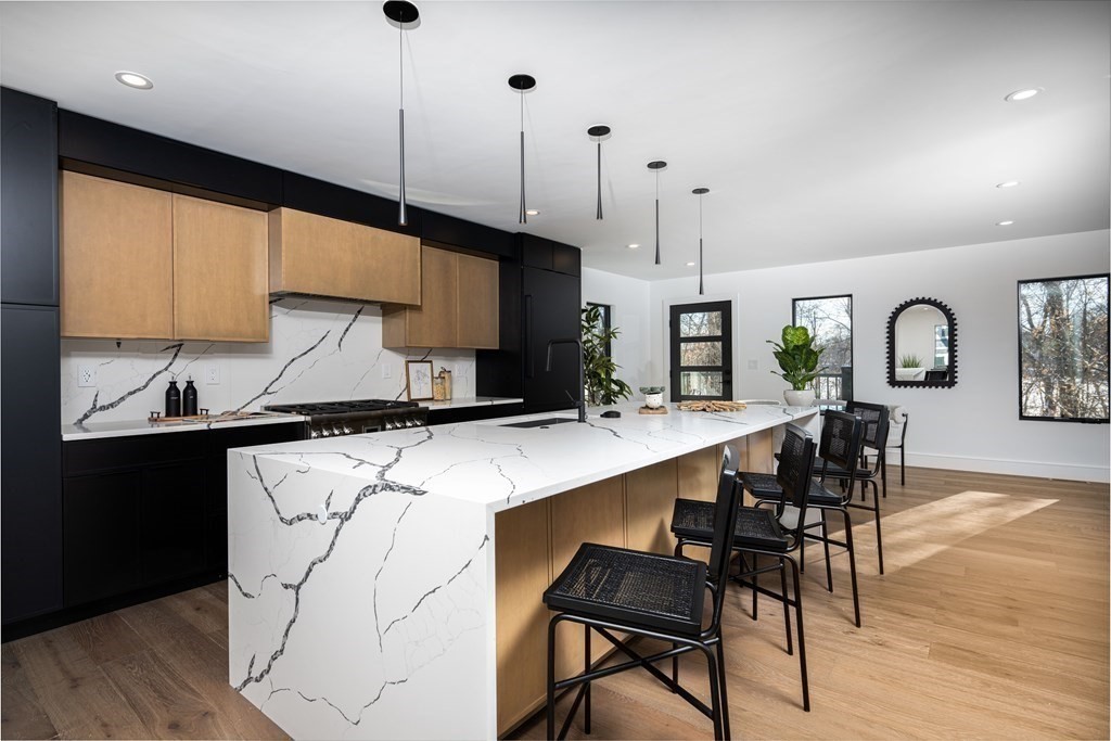 14 Edith Street, Unit 14 Arlington, MA 02474 - Photo 17 of 42 a kitchen with stainless steel appliances kitchen island a table chairs in it and wooden floors