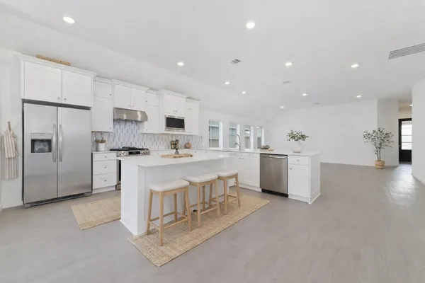 a open kitchen with white cabinets and stainless steel appliances