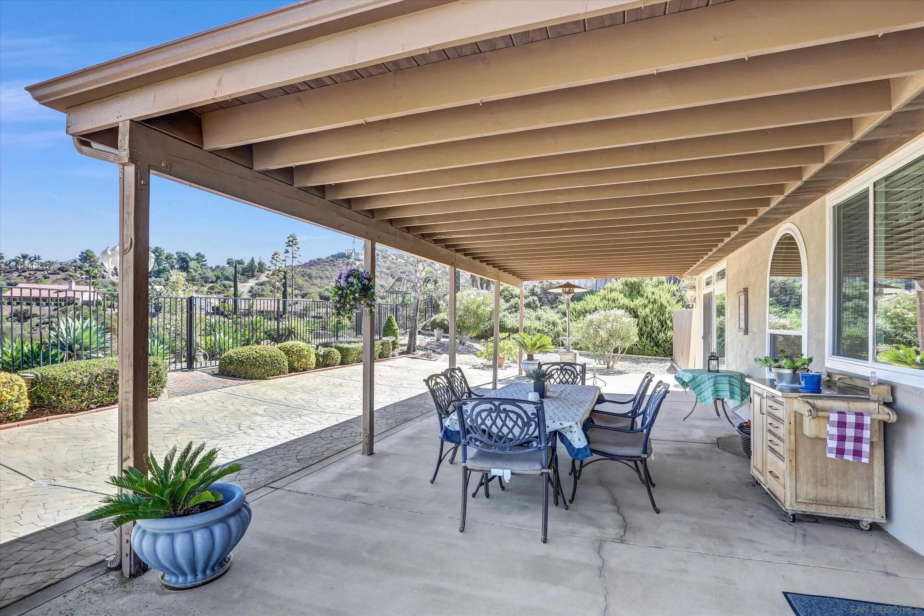 8983 Chestnut Roan Way Alpine, CA 91901 - Photo 31 of 33 a view of a patio with table and chairs potted plants with floor to ceiling window