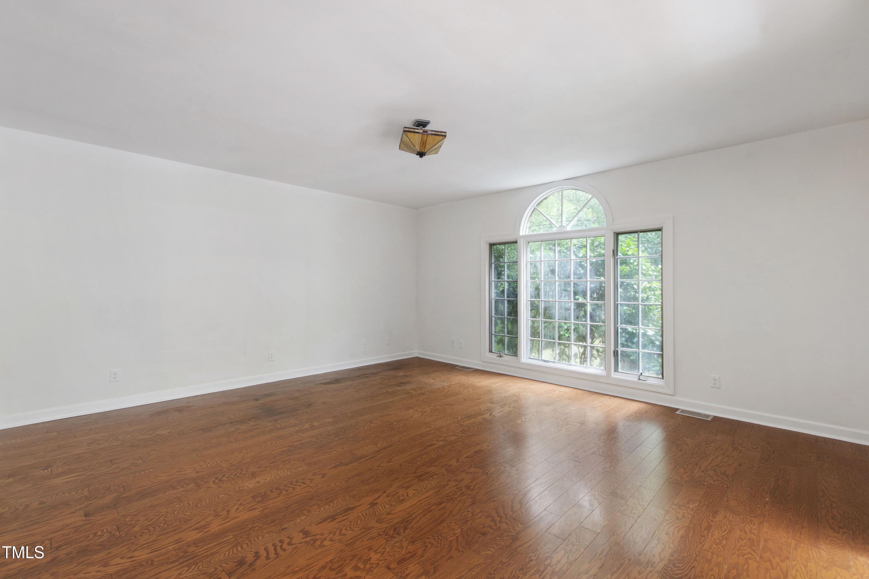 2517 High Ridge Drive Raleigh, NC 27606 - Photo 34 of 69 an empty room with wooden floor chandelier fan and windows