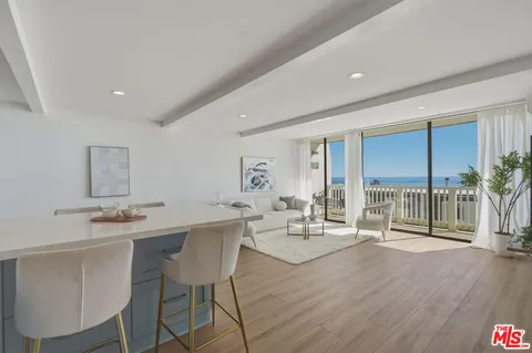a living room with furniture a large window and wooden floor