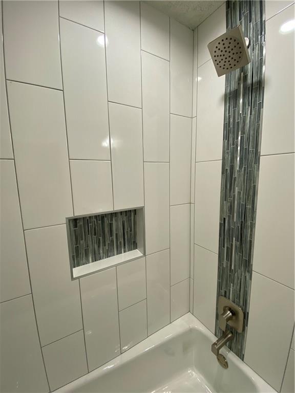 1715 Shadowview Drive, Unit B Austin, TX 78758 - Photo 28 of 28 A sleek, tiled shower-tub combination features a distinctive vertical accent and convenient built-in niche.