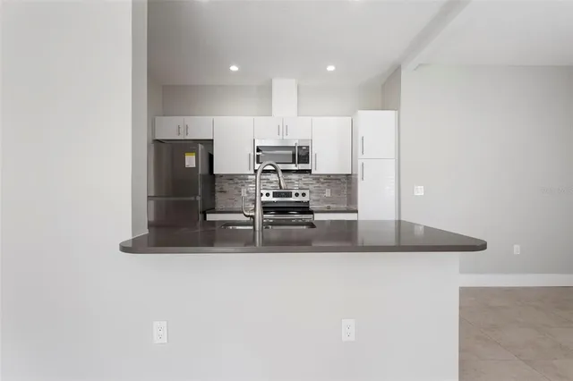 a kitchen with stainless steel appliances granite countertop a refrigerator a stove top oven a sink and dishwasher