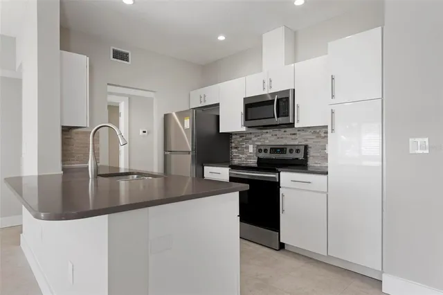 a kitchen with stainless steel appliances granite countertop a refrigerator stove microwave and sink