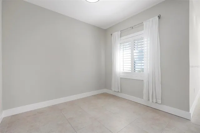 an empty room with chandelier fan and windows