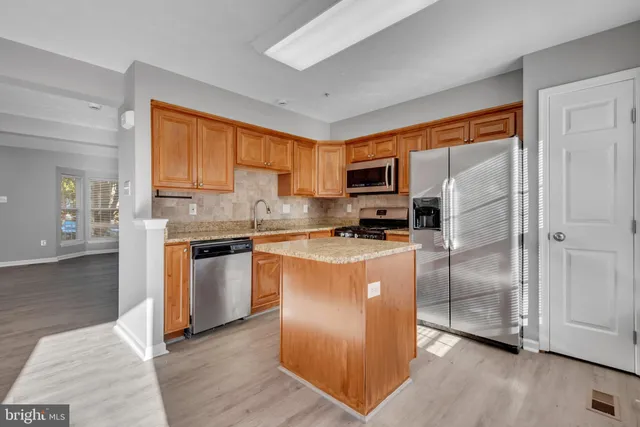 a kitchen with stainless steel appliances granite countertop a refrigerator a stove a sink and a microwave