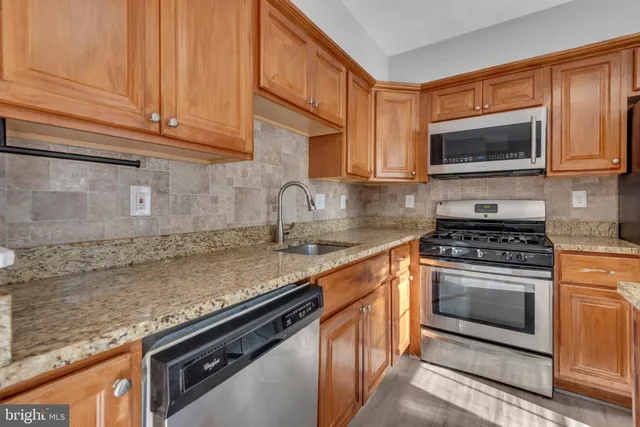 a kitchen with stainless steel appliances granite countertop a sink stove and microwave