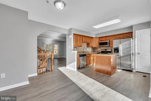 a kitchen with stainless steel appliances granite countertop a refrigerator a stove top oven a sink dishwasher and white cabinets with wooden floor