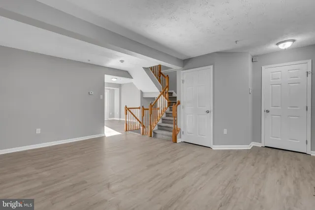 a view of an empty room with wooden floor and stairs