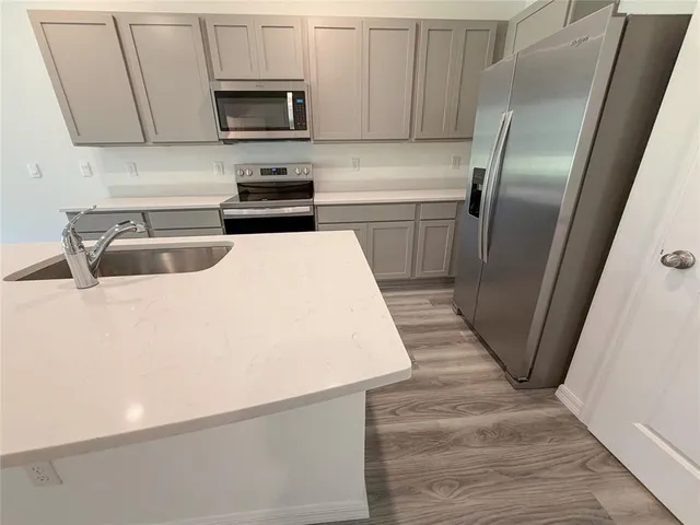a kitchen with kitchen island wooden floors appliances and sink