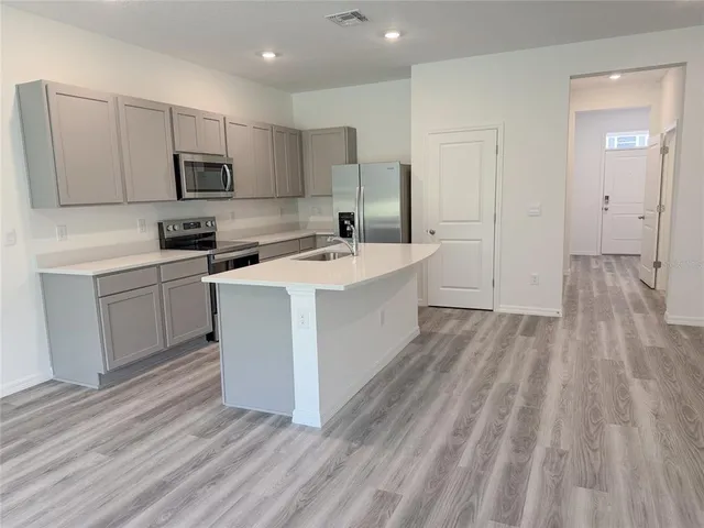 a kitchen with a sink a microwave a refrigerator and cabinets