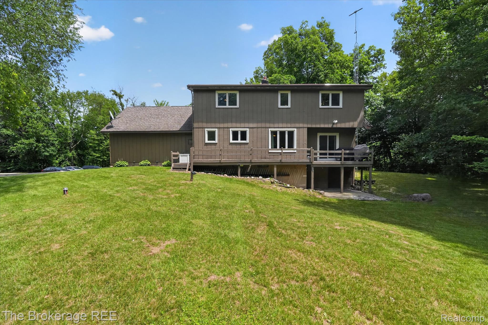 13269 North Genesee Road Clio, MI 48420 - Photo 5 of 67 Expansive green lawn surrounds a two-story home featuring a lower-level deck and upper-level sliding glass door access