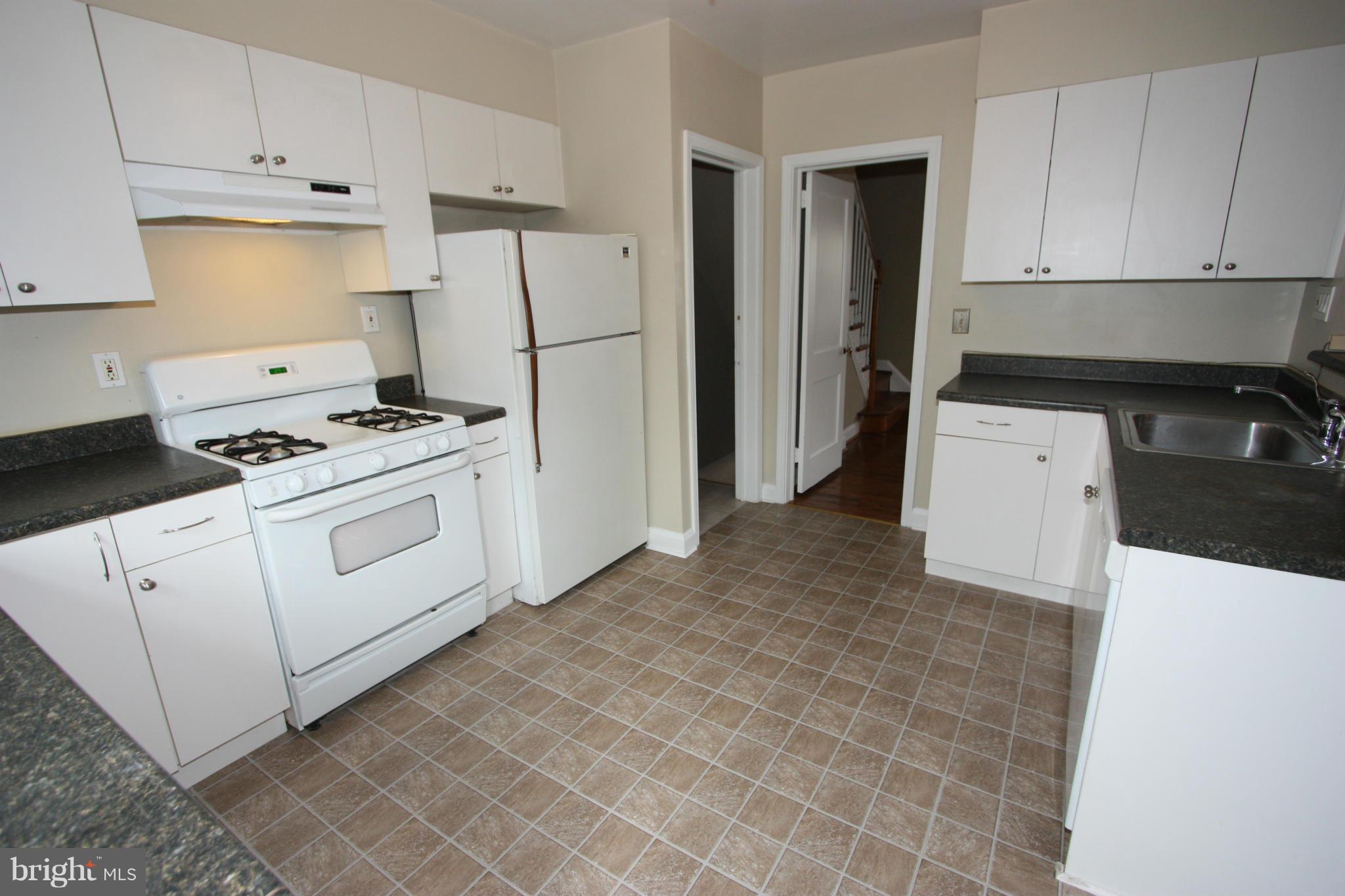 1932 Edgewood Road Parkville, MD 21286 - Photo 5 of 30 a kitchen with a stove a refrigerator and white cabinets
