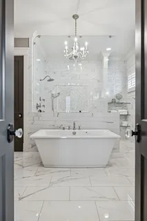 a bathroom with a bathtub a chandelier and a shower