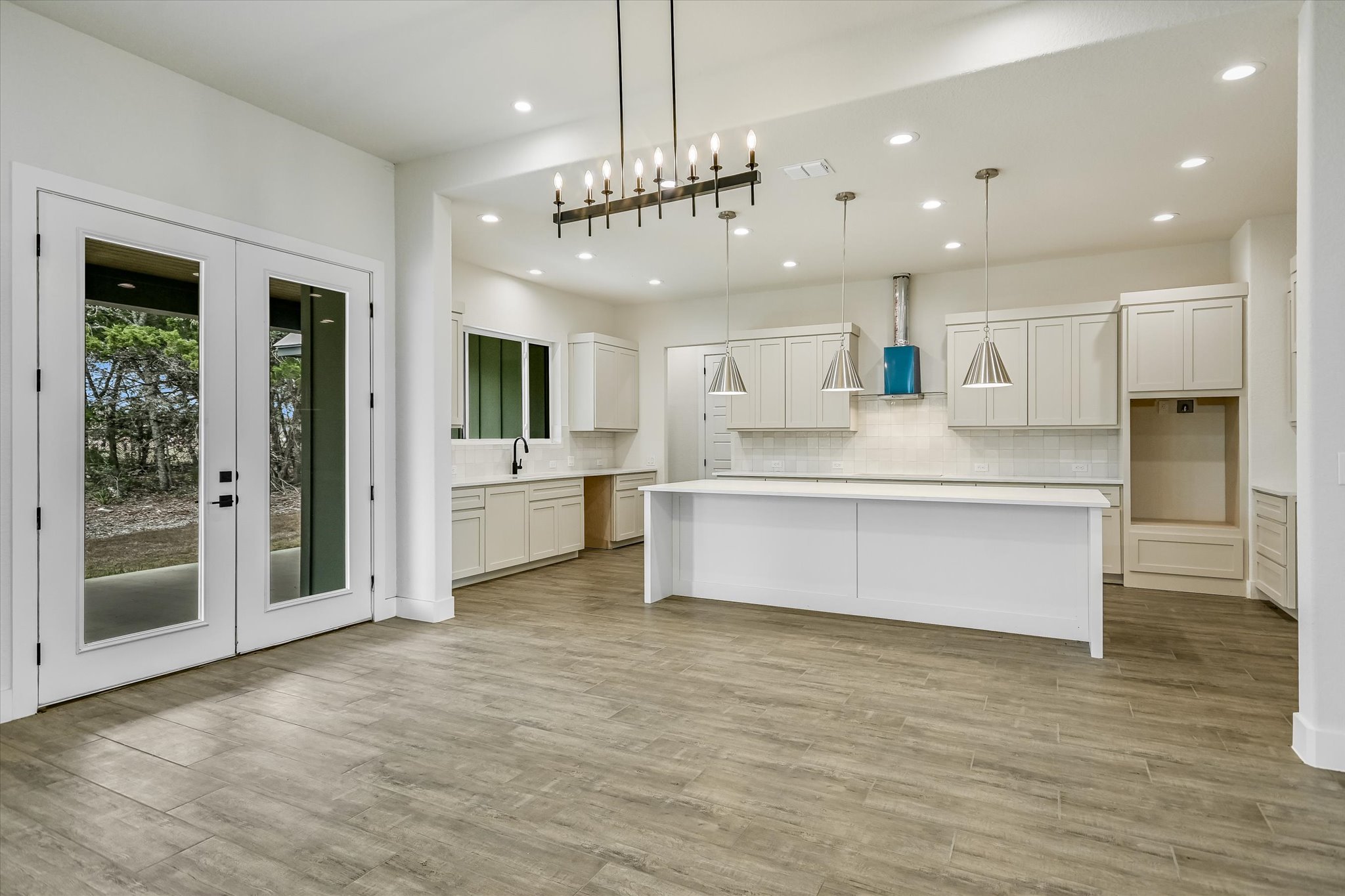 32 Peace Pipe Wimberley, TX 78676 - Photo 6 of 20 Kitchen featuring white cabinetry, french doors, decorative backsplash, and a large island