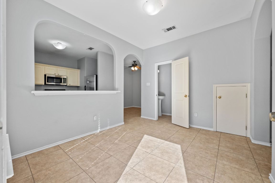 2906 Pearl Street, Unit B Austin, TX 78705 - Photo 9 of 30 Empty room featuring arched walkways, a ceiling fan, and light tile patterned flooring