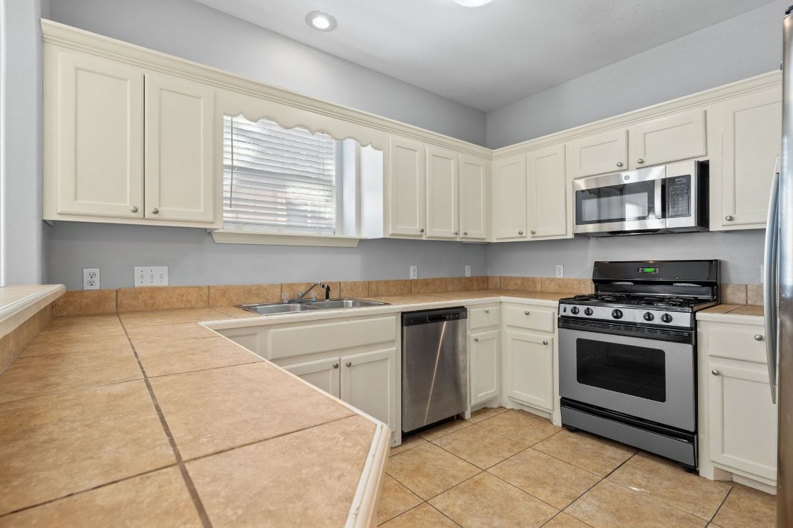 2906 Pearl Street, Unit B Austin, TX 78705 - Photo 10 of 30 Kitchen featuring stainless steel appliances, light tile patterned flooring, and tile counters