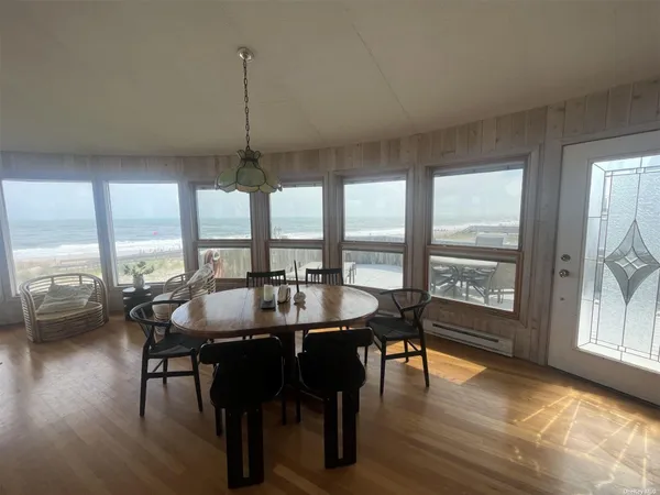 a dining room with wooden floor a chandelier a glass table and chairs