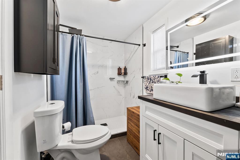 71 Spring Street Nutley, NJ 07110 - Photo 21 of 50 a bathroom with a sink a toilet a mirror and shower