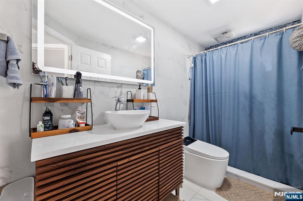 71 Spring Street Nutley, NJ 07110 - Photo 33 of 50 a bathroom with a sink a toilet and shower curtain
