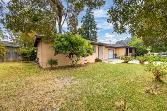 a front view of house with garden and trees