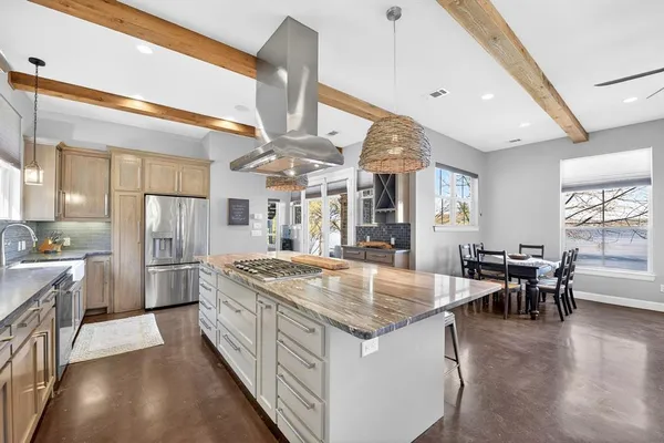 a kitchen with stainless steel appliances kitchen island granite countertop a table chairs sink and cabinets