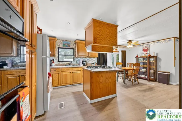 a kitchen with stainless steel appliances granite countertop a refrigerator a stove and a sink with cabinets