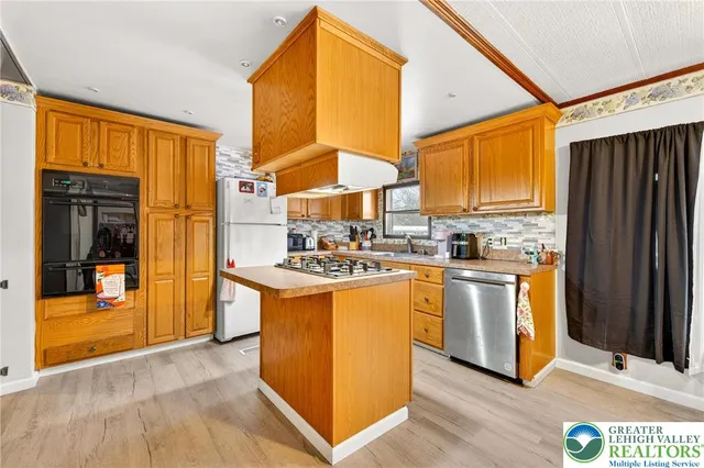 a kitchen with stainless steel appliances granite countertop a refrigerator a sink and a stove with wooden floor