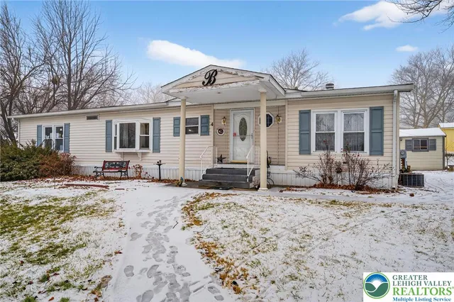 a front view of a house with a yard covered in snow