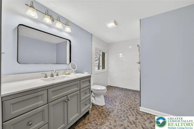 a bathroom with a toilet sink double vanity and mirror