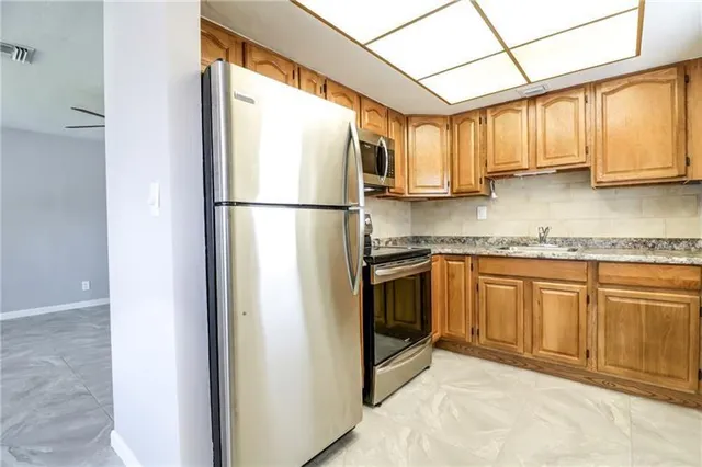 a kitchen with stainless steel appliances granite countertop a refrigerator a sink and white cabinets