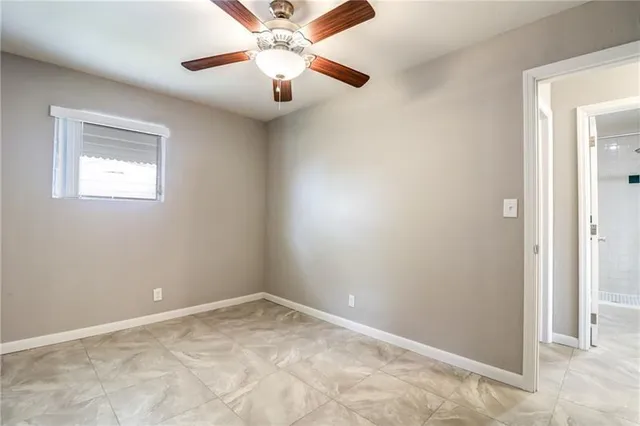 an empty room with a chandelier fan and windows