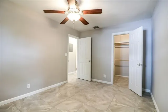 an empty room with closet and a chandelier fan