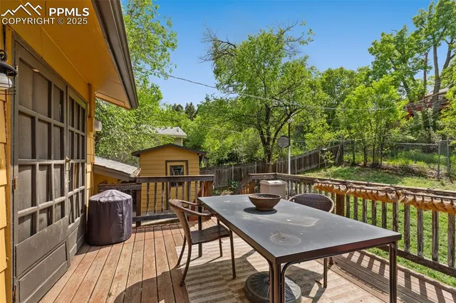 a view of a roof deck with table and chairs with wooden floor and fence