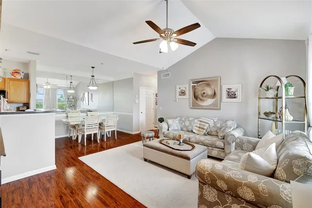a living room with furniture kitchen view and a wooden floor