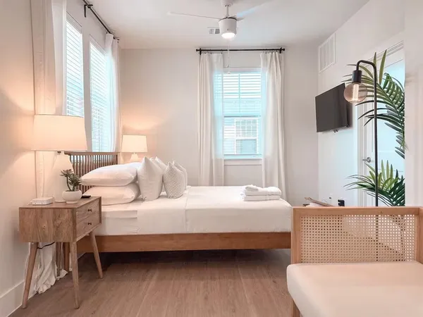 a bedroom with a bed a couch and a potted plant on the dresser