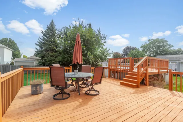 a view of a roof deck with table and chairs a barbeque with wooden floor and fence