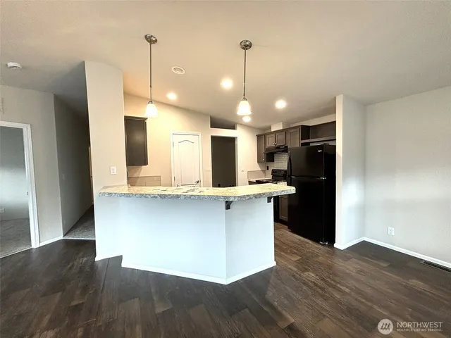 a open kitchen with stainless steel appliances granite countertop a refrigerator a sink and a wooden floor