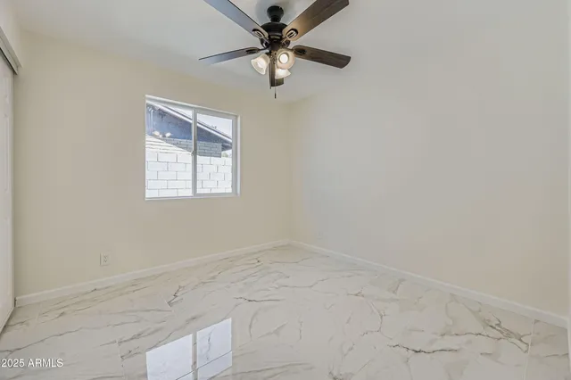 an empty room with windows and fan